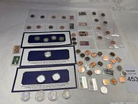 Overview of the entire coin and stamp collection lot including rolls of coins, sleeves with coins, and envelopes with stamps.