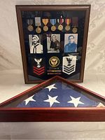 Full view of framed shadow box with medals, photos, patches and adjacent triangular flag case