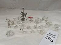Group shot of all clear crystal figurines and metal horse on plain background