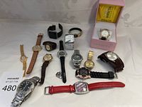 Full view of 12 assorted watches laid out with Invicta box
