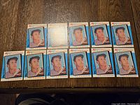 11 identical 1962 Topps Kmart 20th Anniversary Mickey Mantle baseball cards laid out on wood surface.