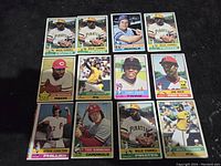 Photo showing 12 1976 Topps baseball cards arranged in three rows on a black background, featuring Hall of Famers including Willie Stargell, George Brett, Joe Morgan, Jim Rice, Steve Carlton, Ted Simmons, and others.
