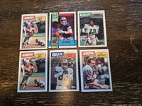 Photo showing six football cards including Troy Aikman rookie, Jerry Rice 2nd year, Joe Montana, Phil Sims, plus three 3rd year cards including Dan Marino and Mark Gastineau.