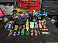Full view of all toy vehicles and remote controlled items displayed on black surface with red tool chest in background