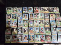 Photo showing 50 assorted 1976 Topps baseball cards laid out in rows, featuring multiple players in various poses and teams.