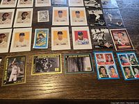 Photo showing a variety of baseball cards laid out on a wooden surface including multiple cards of players.