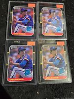 Four 1987 Donruss Greg Maddux rookie baseball cards shown individually in clear protective top loader sleeves, arranged in pairs.