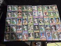 Collection of 50 vintage 1976 Topps baseball cards laid out in rows showing colorful borders and star players.