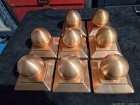 Seven copper ball post caps arranged in a grid, showing tops and overall condition with patina and wear.
