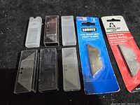Eight razor cutter blade packs showing blister packs and plastic cases of blades, new condition