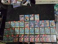 Top-down photo showing multiple rows of sleeved Mark McGwire baseball cards in top-loaders laid out on a dark surface.