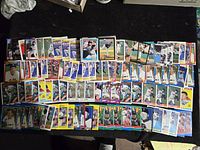 Image showing many rows of Roger Clemens baseball cards arranged on a dark surface, displaying various card styles and designs from multiple vintage sets.