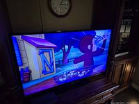 Phillips 57-inch TV displaying an animated scene featuring a character in a cart and blue background.