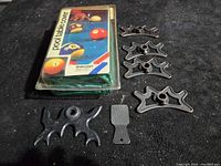 Items laid out on black surface: new pool table cover in package, five metal bridge heads, one small black plastic tip tapper