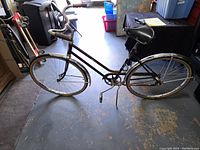 Full side view of the vintage Vista Sophisticate 1960s bicycle showing maroon step-through frame, cream fenders, black saddle, kickstand, rear rack and cream tires.