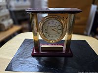 Front view of Vintage Danbury swivel/orb clock showing the wooden base and brass frame.