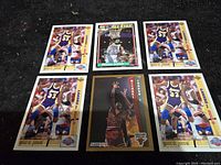 Top view of six basketball cards on dark surface, showing Michael Jordan and Magic Johnson cards.