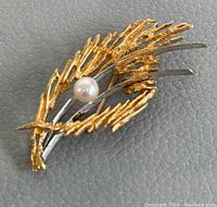 Front angled view of brooch showing textured gold leaf design with pearl center
