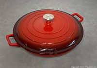 Top-down photo showing red round enamelled cast iron pot with metal knob and side handles.