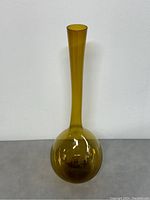 Full view of the amber coloured glass vase showing its tall, slender neck and round base against a plain white background.
