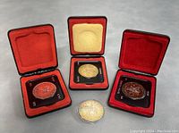 Four Canadian silver dollar coins displayed with three in black/red velvet-lined cases and one in a clear capsule on grey surface.