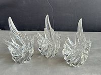 Three clear crystal candleholders with twisted flame-like designs, shown together