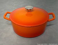 Photo of round orange enamelled cast iron pot with lid and Lagostina metal top knob, two handles on sides.
