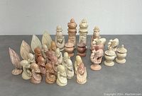 Molded soapstone chess pieces in varying shades arranged with clear details on each piece.