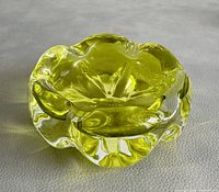 Top angled close-up view of the yellow signed and numbered art glass ashtray showing its thick glass and organic shape.