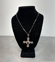 Full front view of necklace on black display bust showing cross pendant and chain