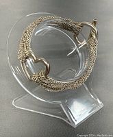 Bracelet draped over clear display stand showing multi‐strand chain and heart motif.