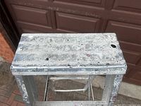 Top view of the ladder's platform showing paint splatters and some surface wear.