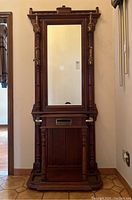 Full front view of the antique style solid wood hall stand with mirror, multi-hook brass coat rack, and letter drawer.