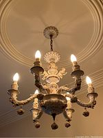 Full view of chandelier hanging from ceiling with six illuminated arms and chain attachment
