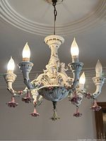 Front view of six-arm chandelier with cherub and floral details