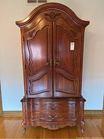 Full front view of armoire showing carved doors and arched crown