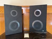 Front view of the pair of vintage black fabric front speakers showing speaker circle outlines.