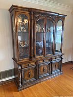 Front view of the vintage oak china cabinet showing top glass display doors, carvings, and bottom cabinet drawers and doors