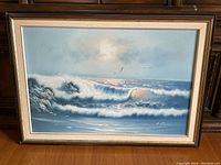 Framed seascape painting showing full artwork with waves, rocks, and flying birds. Image taken to show item condition and framing.