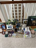 Full view of assorted decorative items on carpet including framed art, floral arrangement, boxes, and glass balls