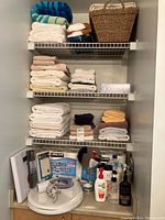 Full closet view showing three shelves filled with neatly folded bath towels in multiple colors and styles with a basket on top shelf