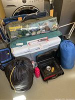 Full lot showing tent, cooler, stove, sleeping bags, chairs, air mattress and water bottle arranged together.