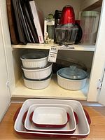 Overall view of shelf with Corningware casseroles, Lagostina items below, and kitchen containers above