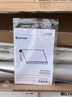 Boxed Costway retractable awning with manual in plastic. Metal frame and fabric rolled and wrapped with foam protective material.