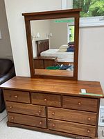 Full view of the wooden dresser with attached mirror reflecting room interior.