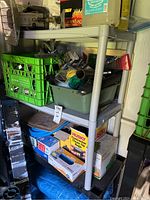 Gray plastic shelving unit with assorted small items including tools, boxes, and supplies.