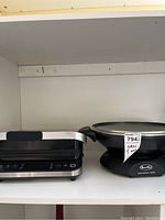Frigidaire electric grill and Breville wok together on a shelf, showing overall condition and scale.