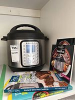 Front view of Instant Pot Duo Plus and three recipe books showing titles and cover designs.