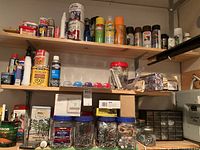 Wide view showing shelves with spray paint cans, wood stains, hardware jars, and adhesives.