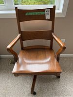 Front view of the wooden swivel office chair showing curved armrests, contoured seat, and backrest with three horizontal wooden slats.